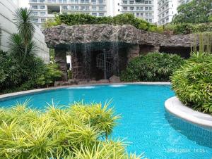 a large blue swimming pool with a waterfall at Stars & Sunsets Sky Views 1br Iguazu Tower in Manila