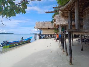 a boat on a beach next to a hut at Yefkabu Homestay Raja Ampat in Waisai