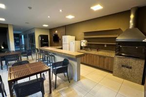 a large kitchen with a counter and tables and chairs at Apartamento Térreo Climatizado na Avenida Artêmia Pires Freitas in Feira de Santana