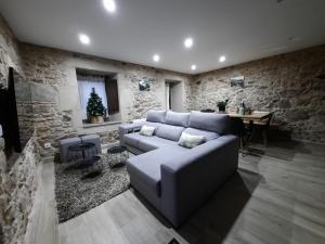 ein Wohnzimmer mit einer Couch und einer Steinwand in der Unterkunft Casal da Ponte nas Rías Baixas in Boiro