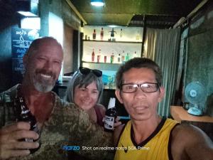 two men and a woman posing for a picture in a bar at El Nido Bayview in El Nido