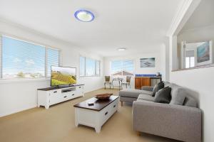 Una sala de estar con un sofá y un televisor. en The Blue Cottage, en Ulladulla