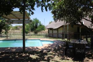 a house with a pool and a table and a tree at Honey Lodge in Klipdrift