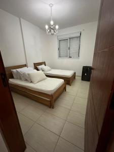 a room with two beds and a chandelier at Apartamento maravilhoso na Pitangueiras Guarujá in Guarujá