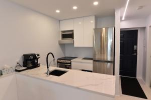 a kitchen with white cabinets and a stainless steel refrigerator at Upscale Modern Apartment in Whistler