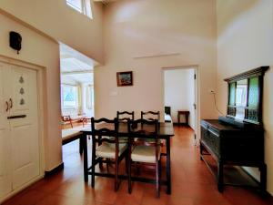 a dining room with a table and chairs and a piano at The Cosy Cottage in Coonoor