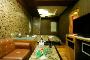 ein Wohnzimmer mit Sofa und Fernseher in der Unterkunft HotelD 大宮店 in Saitama