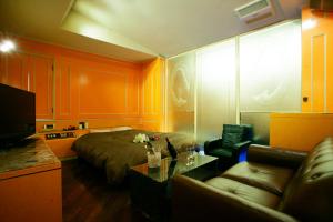 ein Wohnzimmer mit einem Bett und einer Couch in der Unterkunft HotelD 大宮店 in Saitama