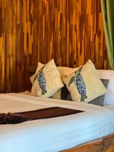 a bed with white pillows and a wooden wall at Homebeach Resort เกาะล้าน in Ko Larn