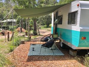 阿格奈什沃特Green Anchorage Bush Stay的一辆房车，配有帐篷和椅子，停放在垫子上