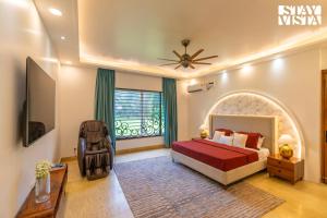 Un dormitorio con una cama y una ventana grande. en StayVista at Imperial Isle 4BHK Luxury Villa with FREE BF, Outdoor Pool in Sohna Delhi, en Sohna
