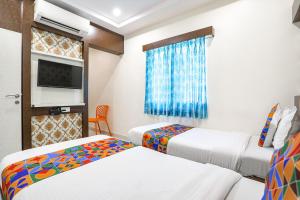 a hotel room with two beds and a tv at FabExpress Geet Residency in Mumbai