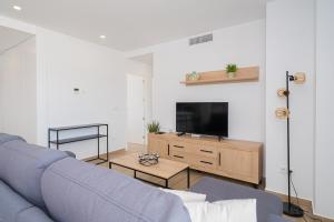 a living room with a blue couch and a tv at Valerie in Orihuela
