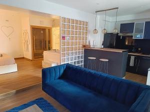 a living room with a blue couch and a kitchen at Bulle Evasion in Triel-sur-Seine