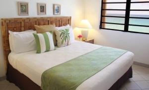 a bedroom with a large bed with green and white pillows at Carimar Beach Club in Meads Bay
