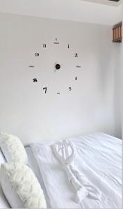 a white bed with a clock on the wall at Cozy Staycation in Manila +3 photos