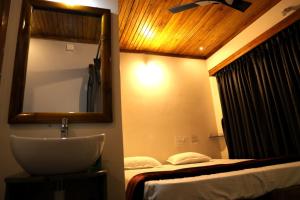 a bathroom with a sink and a mirror and a bed at Niyati Home Stay in Gokarna