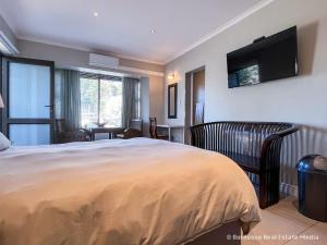 a bedroom with a bed and a television on the wall at 7Pillars Shiraz in Durbanville