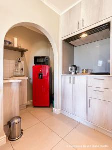 a red refrigerator in a kitchen with white cabinets at 7Pillars Shiraz in Durbanville +7 photos