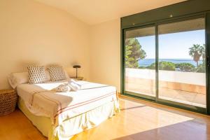 une chambre avec un lit et une grande fenêtre dans l'établissement Villa Les Oliveres - Lux Houses Experience, à Lloret de Mar 37 autres photos