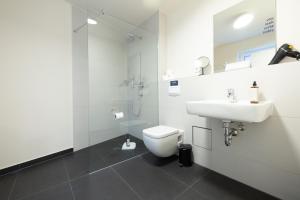 ein weißes Badezimmer mit Toilette und Waschbecken in der Unterkunft BRIGHT Leipzig Zentrum-West Stadion in Leipzig + 11 Fotos