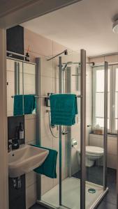 a bathroom with a sink and a shower with green towels at NOX Business Apartments in Tuttlingen +7 photos