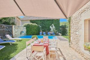 un patio avec une table et des chaises et une piscine dans l'établissement La Forge maison spacieuse 8 pers Lascaux Sarlat, à Saint-Amand-de-Coly