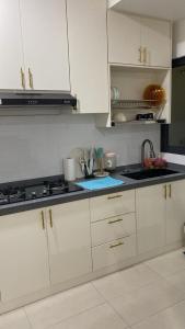 a kitchen with white cabinets and a sink at Irdina Homestay in Banting