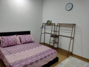 a bedroom with a purple bed and a clock on the wall at Irdina Homestay in Banting
