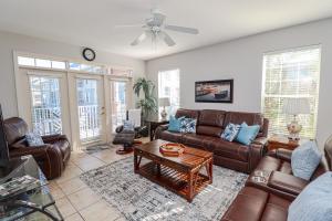 een woonkamer met lederen meubels en een plafondventilator bij Seaside at Anastasia D205 in St. Augustine