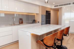 a kitchen with white cabinets and a counter with chairs at Azzure Bliss at Bokarina Beach in Kawana Waters
