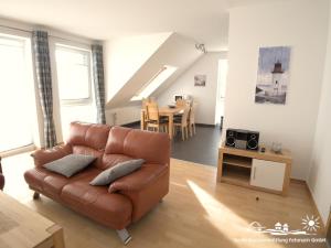 a living room with a brown leather couch and a table at 53 Ferienwohnung im Fritz-Bleyl-Weg 14 OG rechts in Burg auf Fehmarn