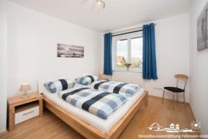 a bedroom with a bed with blue and white pillows at 53 Ferienwohnung im Fritz-Bleyl-Weg 14 OG rechts in Burg auf Fehmarn