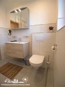 a bathroom with a toilet and a sink and a mirror at 53 Ferienwohnung im Fritz-Bleyl-Weg 14 OG rechts in Burg auf Fehmarn +13 photos