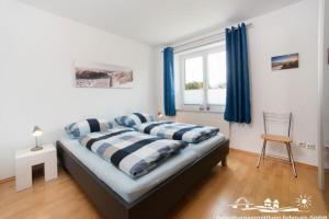 a bedroom with a bed with blue curtains and a chair at 51 Ferienwohnung im Fritz-Bleyl-Weg 14 EG rechts in Burg auf Fehmarn