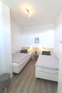 two beds in a room with white walls and wooden floors at 55 Ferienwohnung Strandnest 2 Strandburg App.0.2 links in Burgtiefe auf Fehmarn 