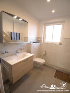 a bathroom with a sink and a toilet and a window at 54 Ferienwohnung im Fritz-Bleyl-Weg 14 OG links in Burg auf Fehmarn