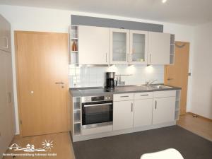 a kitchen with white cabinets and a sink at 56 Ferienwohnung im Fritz-Bleyl-Weg 14 DG links in Burg auf Fehmarn +11 photos