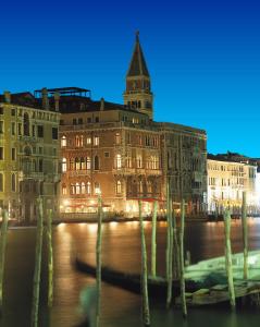 a building with a clock tower and a boat in the water at Bauer Palazzo in Venice