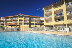 un hôtel avec une piscine en face d'un bâtiment dans l'établissement Vacancéole - Résidence Alizéa Beach, à Valras-Plage