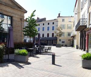 an empty courtyard with tables and chairs and an umbrella at Appartement À deux pas de tout in Issoire