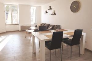 a living room with a table and chairs and a clock at Appartement À deux pas de tout in Issoire +3 photos