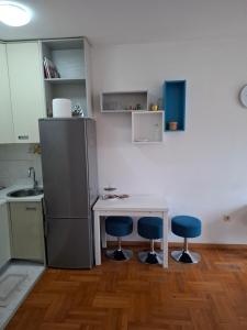 a kitchen with a small table and two blue chairs at Dina's Place in Podgorica