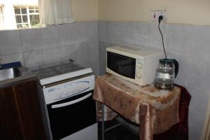 a kitchen with a stove and a microwave on a table at Tinotenda Cottage in Harare