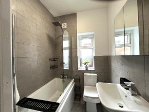 a bathroom with a tub and a toilet and a sink at Spacious home sleeps 8 Nr Etihad Coop Live & City in Manchester