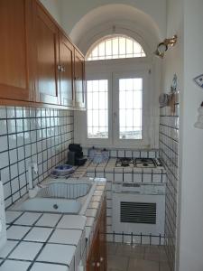 uma cozinha com azulejos brancos e um fogão forno superior em Casa Scalo Grande em Acireale