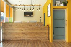 a restaurant with a wooden counter and yellow walls at Fullroom 77 Srinakarin in Samutprakarn