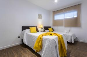 a bedroom with two beds with yellow pillows at Playa Victoria Paseo Marítimo 3 Rooms in Cádiz