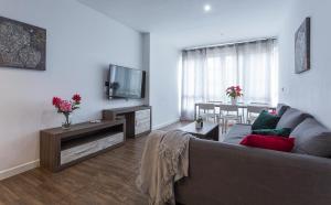 a living room with a couch and a tv and a table at Playa Victoria Paseo Marítimo 3 Rooms in Cádiz +10 photos