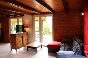 a living room with a couch and a tv at Bouleau - Chalet en bois dans son écrin de verdure in Écromagny